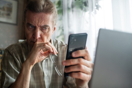 Senior man looking seriously at smartphone